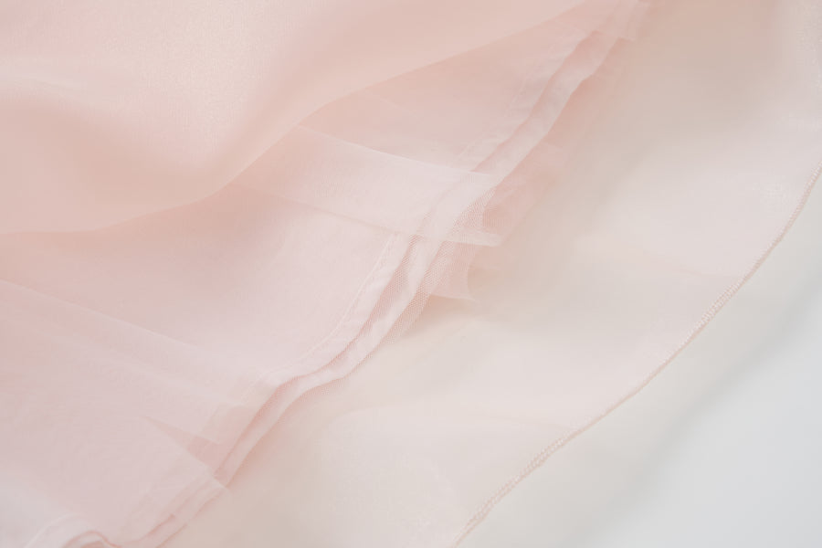 Close-up of the Blush Whisper Dress by KIKI and JOJO, featuring light pink sheer layers with soft folds and a slightly translucent look, perfect for princess-style outfits or embellished with delicate 3D floral appliqués.