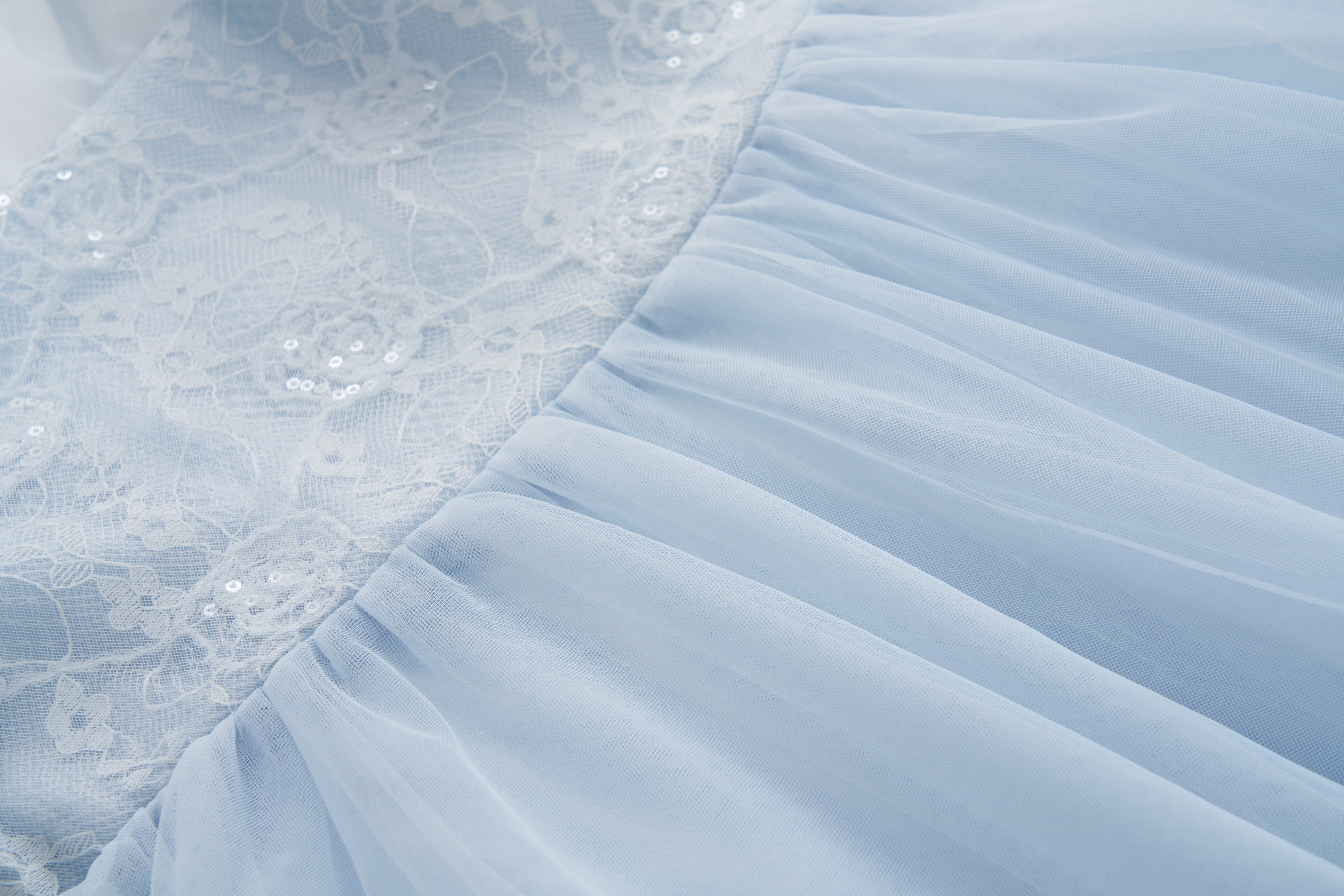 Close-up of the Sky Whisper Dress by KIKI and JOJO, showcasing light blue puff sleeves, a sequin lace bodice, and a gathered tulle skirt.
