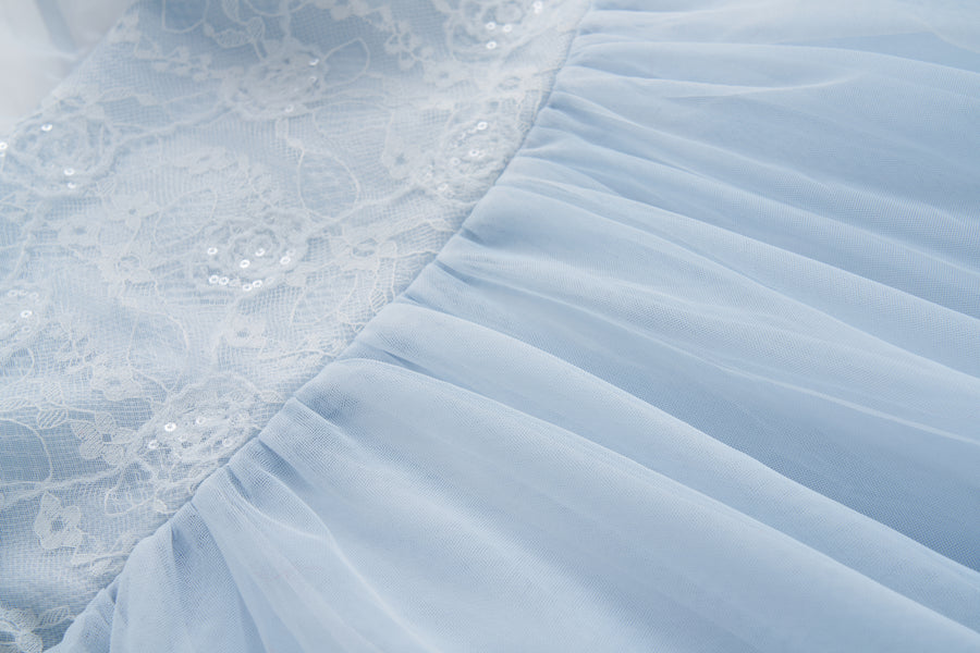 Close-up of the Sky Whisper Dress by KIKI and JOJO, showcasing light blue puff sleeves, a sequin lace bodice, and a gathered tulle skirt.