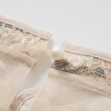 Close-up of the Jade Whisper Dress by KIKI and JOJO, featuring two sheer fabric panels with embroidered florals and metallic accents, joined by a pearl button—capturing the delicate elegance inspired by the cheongsam.