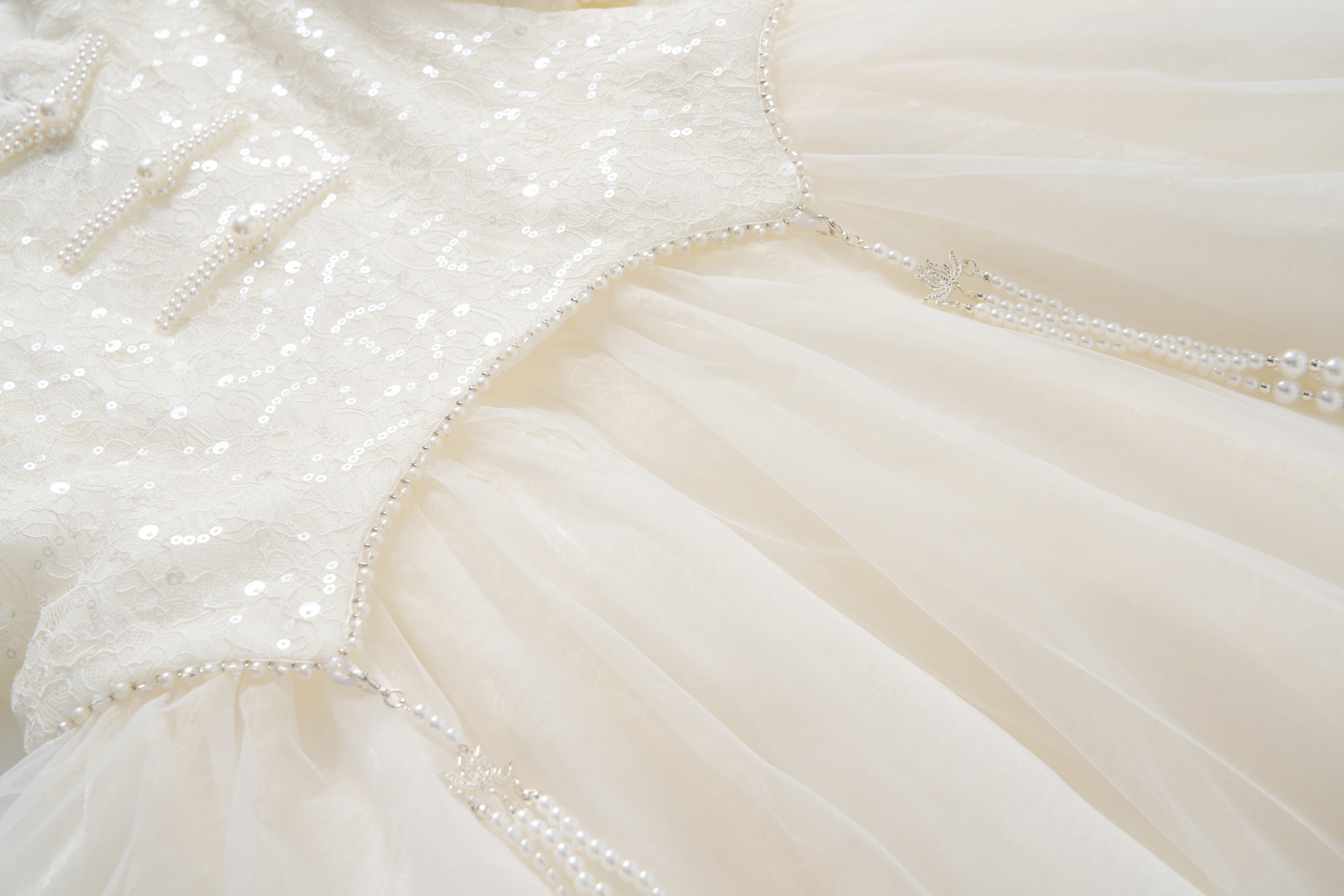 Close-up of the Orchid Whisper Dress by KIKI and JOJO, showcasing a sequin embroidered lace bodice, tulle skirt, and delicate pearl bead embellishments.