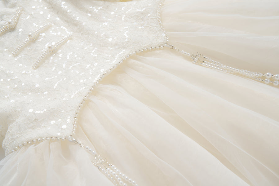 Close-up of the Orchid Whisper Dress by KIKI and JOJO, showcasing a sequin embroidered lace bodice, tulle skirt, and delicate pearl bead embellishments.