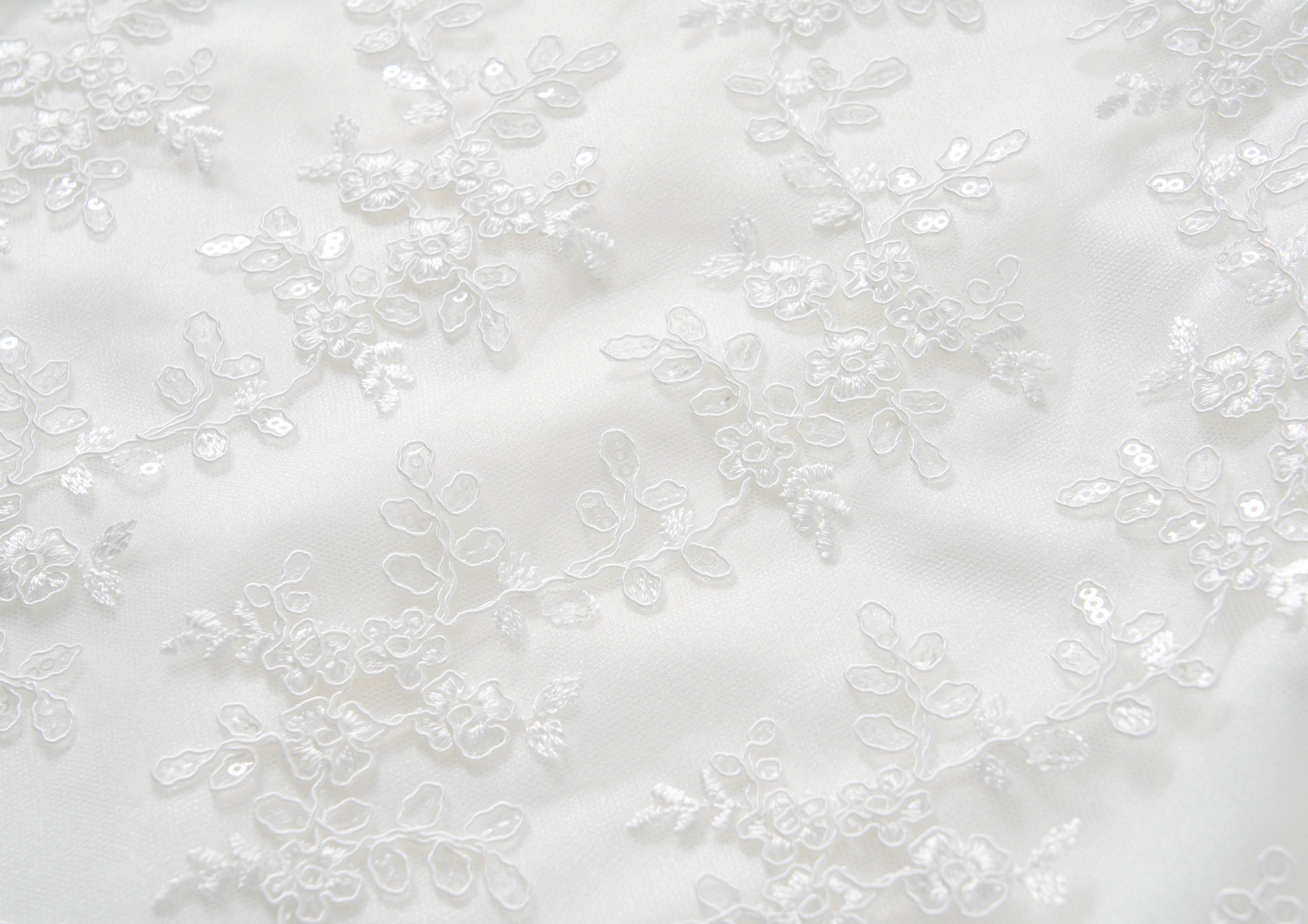 Close-up of the Twinkle Whisper Dress by KIKI and JOJO, featuring white lace fabric with floral embroidery and delicate sequins—ideal for anyone who loves an elegant embroidered lace or soft floral pattern look.