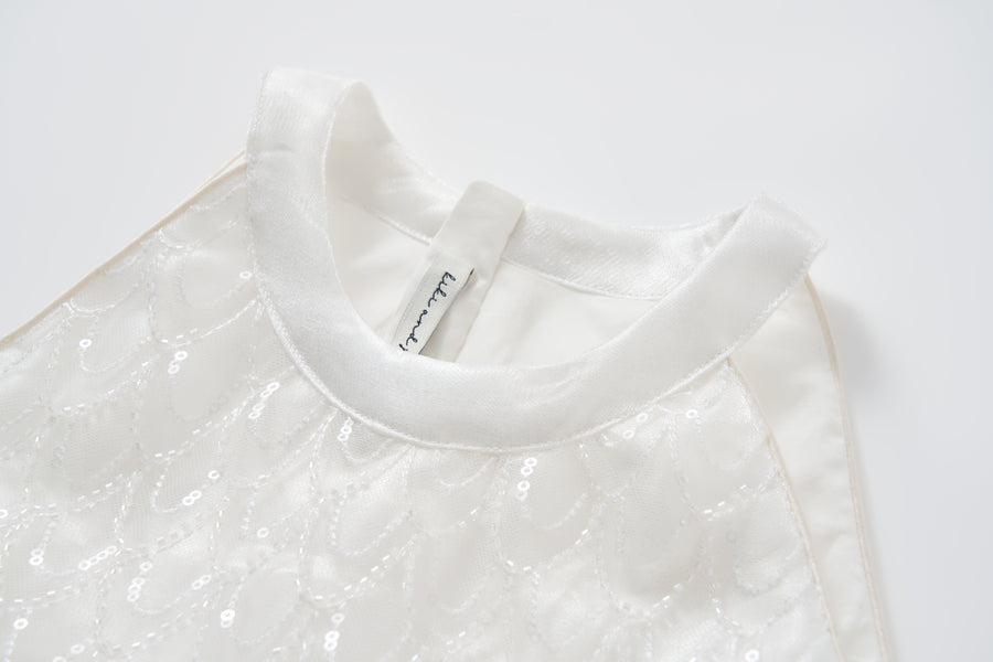 Close-up of the KIKI and JOJO Pearl Glow Whisper Dress—sleeveless with satin collar, delicate sequin patterns, and subtle beaded embroidery—laid flat on a white surface.