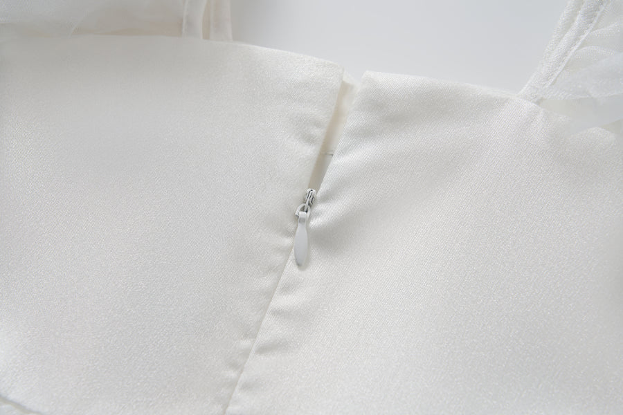 Close-up of the Cloud Whisper Dress by KIKI and JOJO, crafted from shiny white tulle with a discreetly partially closed side zipper.