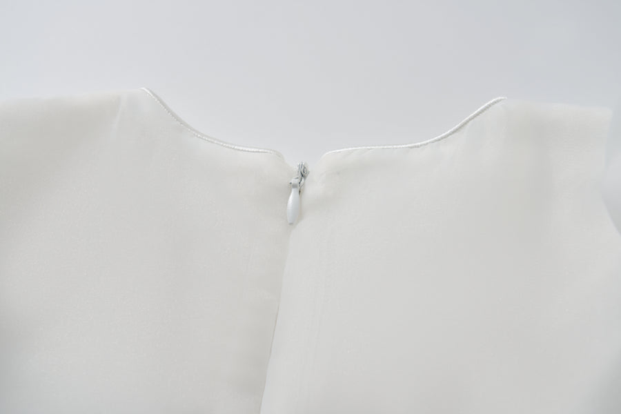 Close-up of the back neckline of the KIKI and JOJO Ballerina Whisper Dress in white, showing a small white zipper partially closed at the top.