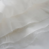 Close-up of layered white sheer fabric with delicate lace and stitched edges—perfect for the Whisper Bloom Dress by KIKI and JOJO, highlighting its ethereal texture and elegant details.