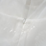Close-up of the Whisper Bloom Dress by KIKI and JOJO—a white mini dress with floral embroidery, zipper closure, sheer fabric adorned with subtle sequins, and delicate bead accents.