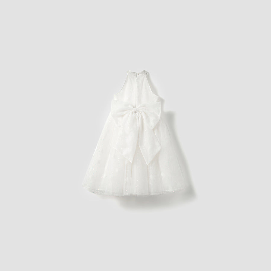 The Butterfly Whispers Dress by KIKI and JOJO is a white satin A-line halter dress with a large back bow, displayed on a plain light gray background. Its unique design and flattering silhouette exude elegant charm.