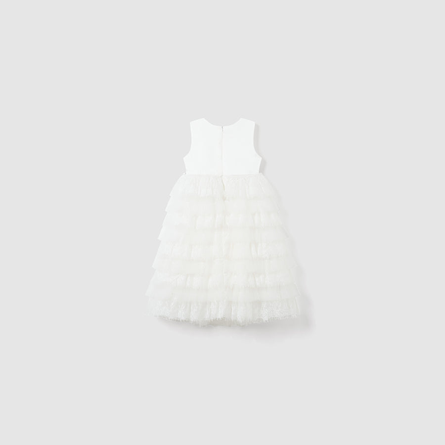The Monochrome Whisper Dress by KIKI and JOJO features a sleeveless white lace ruffle design, a fitted bodice, and a long tiered skirt, shown against a plain light gray background.