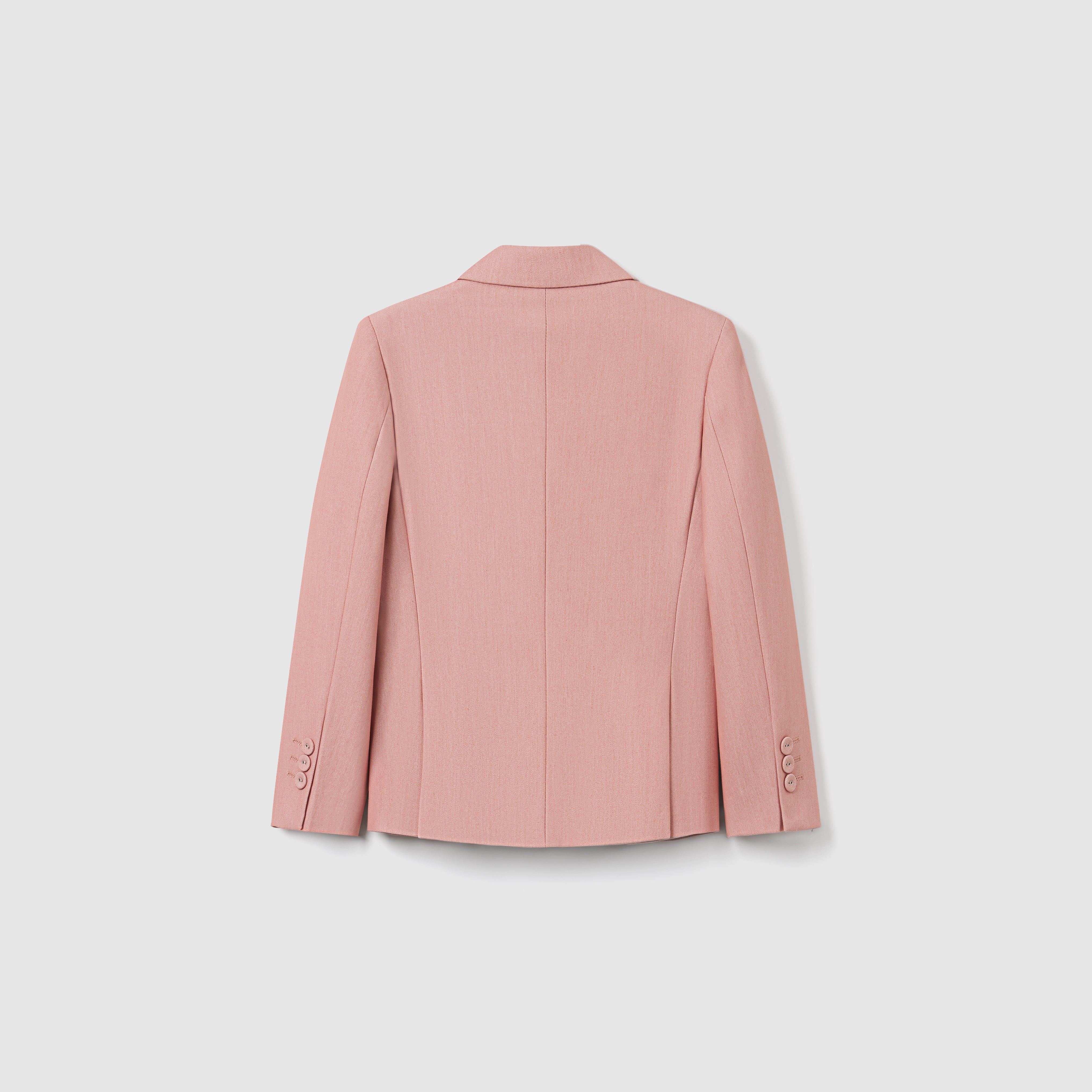The Blush Reverie Suit Jacket by KIKI and JOJO is displayed from the back, showcasing its light blush pink color, double-breasted design, long sleeves, and buttoned cuffs against a plain white background.