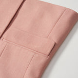 Close-up of the Blush Reverie Suit Jacket by KIKI and JOJO, showing the blush pink sleeve and pocket on a white surface, with focus on the button detail and fabric texture.