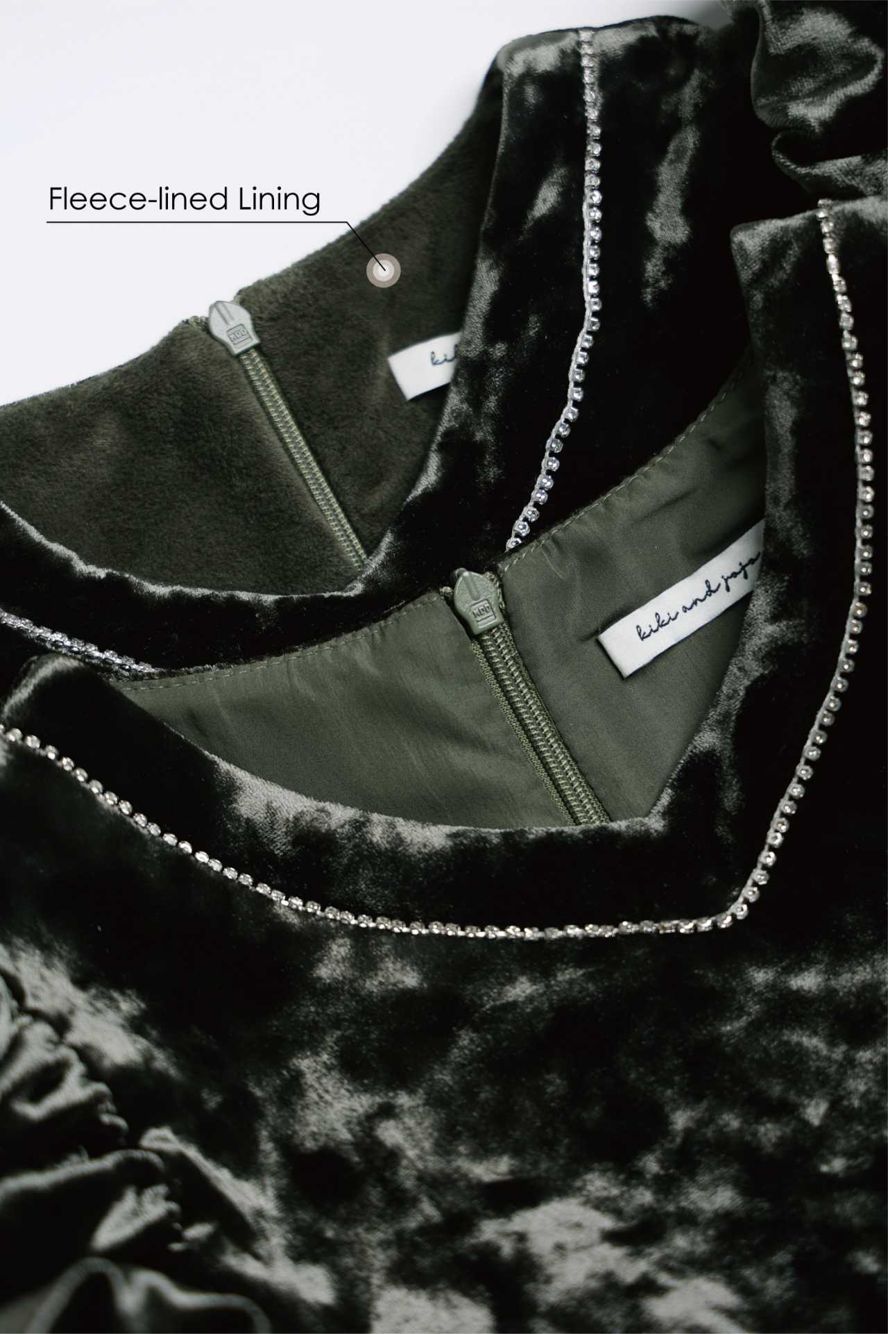 Close-up of the KIKI and JOJO Girls Velvet Puff Sleeve Dress in Forest Green, featuring rhinestone trim, green zipper, and fleece-lined lining—perfect for special occasions.