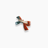 The KIKI and JOJO Girls Bow Hair Clip - Nature Palette features marbled red and deep forest green sections with a bow design and a gold metal clasp on the back.