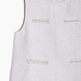 The KIKI and JOJO Girls Elegance A-Line Chiffon Trim Dress in champagne features a sleeveless, textured design with four decorative front details and a back zipper closure.