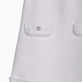 Close-up of the KIKI and JOJO Girls Pearlescent Elegance Tweed Dress in Soft Champagne, featuring two fringed front pockets, pearlescent gold threads, and a round metal button on the left pocket.