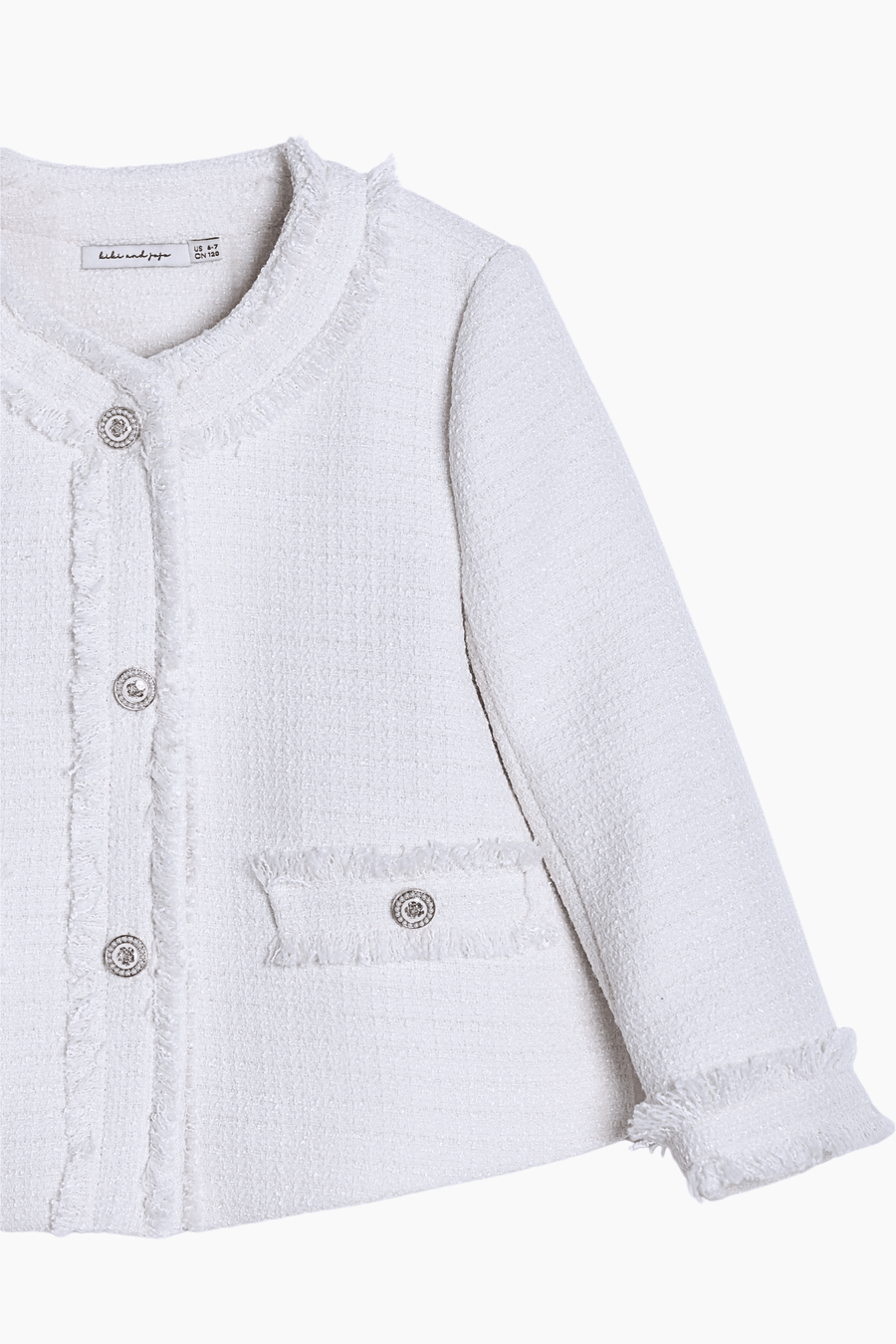 The Girls Pearlescent Elegance Tweed Jacket in Soft Champagne by KIKI and JOJO features a finely woven texture, pearl-like buttons, a round collar, front pockets, and frayed edges for timeless style.
