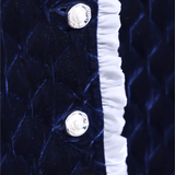 Close-up of the Girls Quilted Ruffle Jacket in Sapphire Blue by KIKI and JOJO, showcasing diamond-quilted velvet, two petal-shaped buttons, and a white ruffled edge trim.