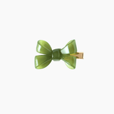 The KIKI and JOJO Girls Sheer Double Bow Hair Clip in Moss Olive features a green, double bow design with a gold metal clasp and pearl-like shimmer, shown against a plain white background.