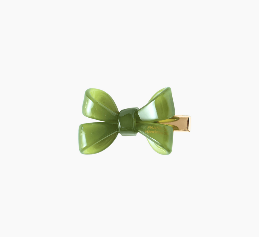 The KIKI and JOJO Girls Sheer Double Bow Hair Clip in Moss Olive features a green, double bow design with a gold metal clasp and pearl-like shimmer, shown against a plain white background.