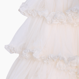 Close-up of the Girls Sparkle Sleeveless Tulle Dress in champagne by KIKI and JOJO, featuring layered tulle, ruffled detailing, and decorative trim, photographed against a plain background.
