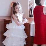 A girl in a KIKI and JOJO Girls Sparkle Sleeveless Tulle Dress - Champagne stands by the kitchen counter, while another girl in a red dress faces away near the sink.