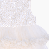 The KIKI and JOJO Girls Sparkle Sleeveless Tulle Dress in Champagne features a sequined bodice, tulle skirt, and ruffled waist detail, displayed against a plain background.