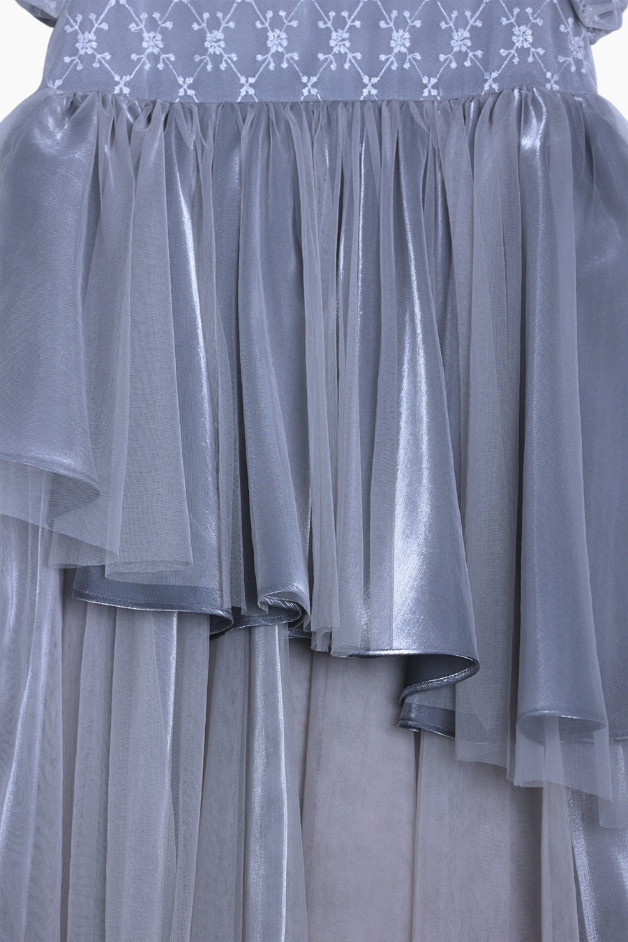 Close-up of the KIKI and JOJO Girls Velvet Asymmetrical Hem Puff Sleeve Dress in gray, featuring a sheer layered tulle skirt and a bodice with white jacquard embroidery and floral patterns.