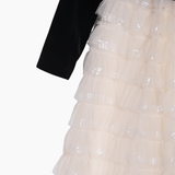 A close-up of the KIKI and JOJO Girls Velvet & Tulle Sparkle Dress in Black/Ivory, featuring a black long-sleeve top and a layered ivory tulle skirt adorned with sequins.