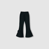 The Petal Whisper Dress Pants by KIKI and JOJO feature a black flared silhouette, elastic waistband, back pockets, and bow details at the hem. Made from stretchy fabric, they're shown against a plain light background.