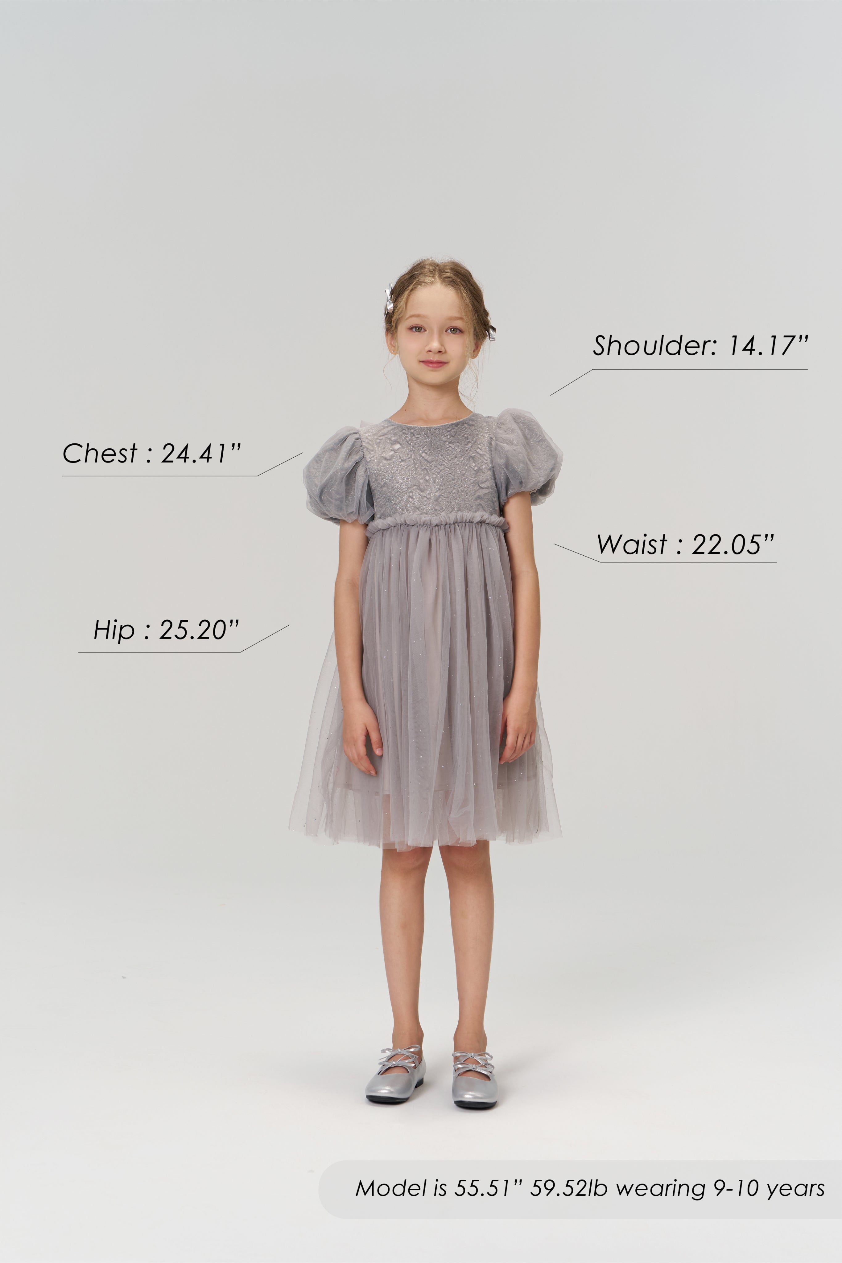 A young girl stands facing forward in the KIKI and JOJO Dusk Whisper Dress with silver shoes. Chest, hip, waist, and shoulder measurements are labeled. She is 55.51", 59.52lb, wearing size 9-10 years.