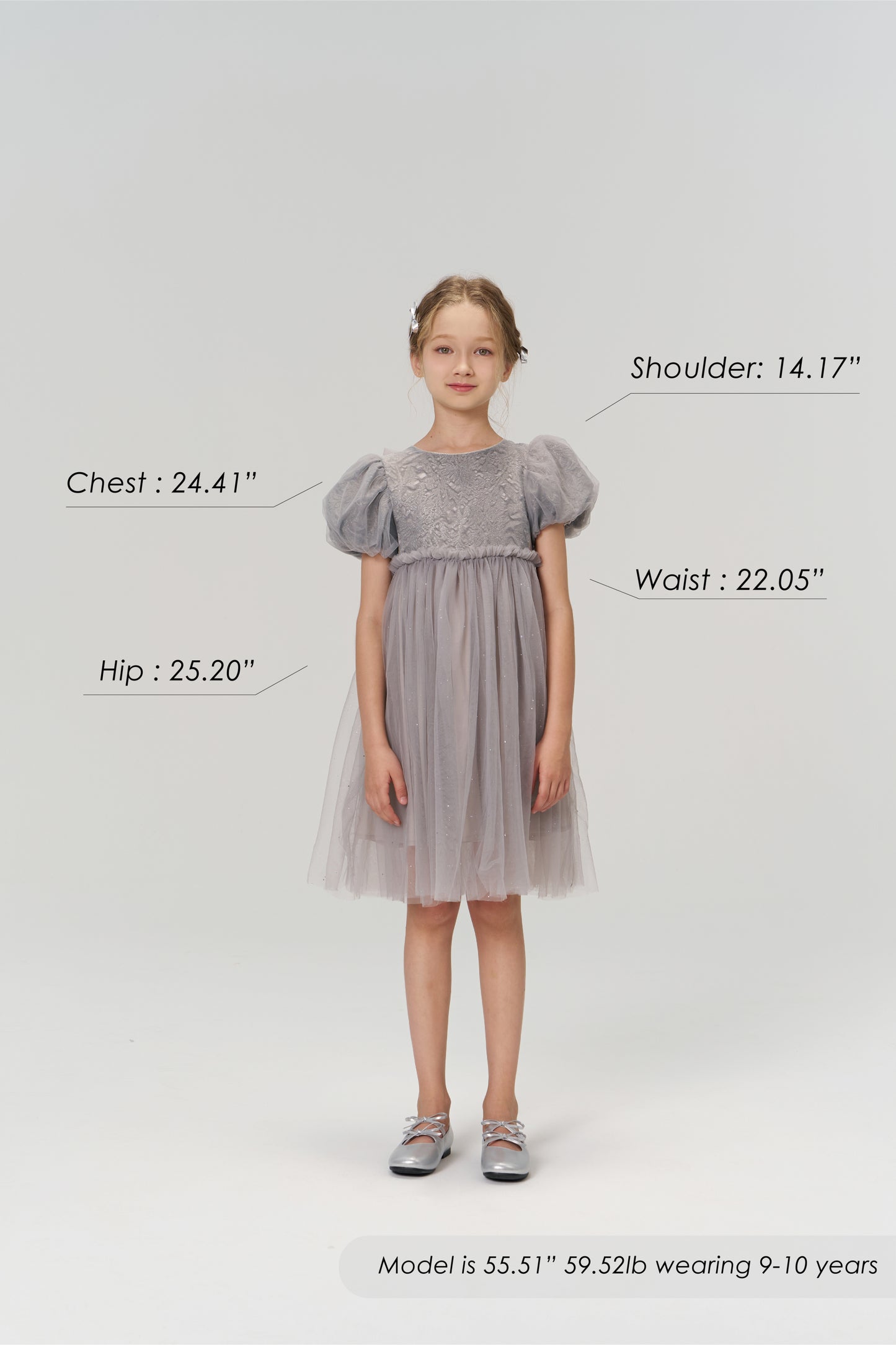 A young girl stands facing forward in the KIKI and JOJO Dusk Whisper Dress with silver shoes. Chest, hip, waist, and shoulder measurements are labeled. She is 55.51", 59.52lb, wearing size 9-10 years.